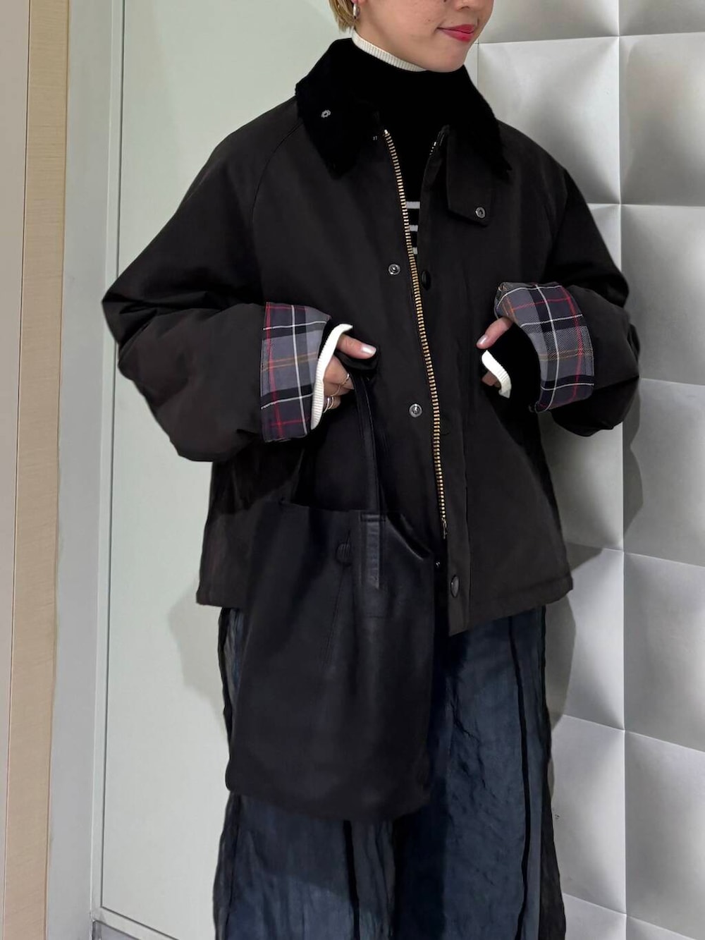 ブラック系のニット/セーター、ブルー系のデニムパンツ、ブラック系のその他アウターを着用したレディースの秋コーディネートの4枚目の写真