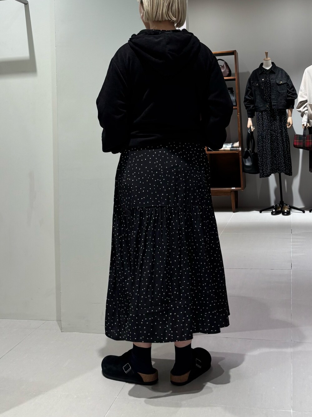 ブラック系のパーカー、ブラック系のワンピース、ブラック系のサンダルを着用したレディースの秋コーディネートの3枚目の写真