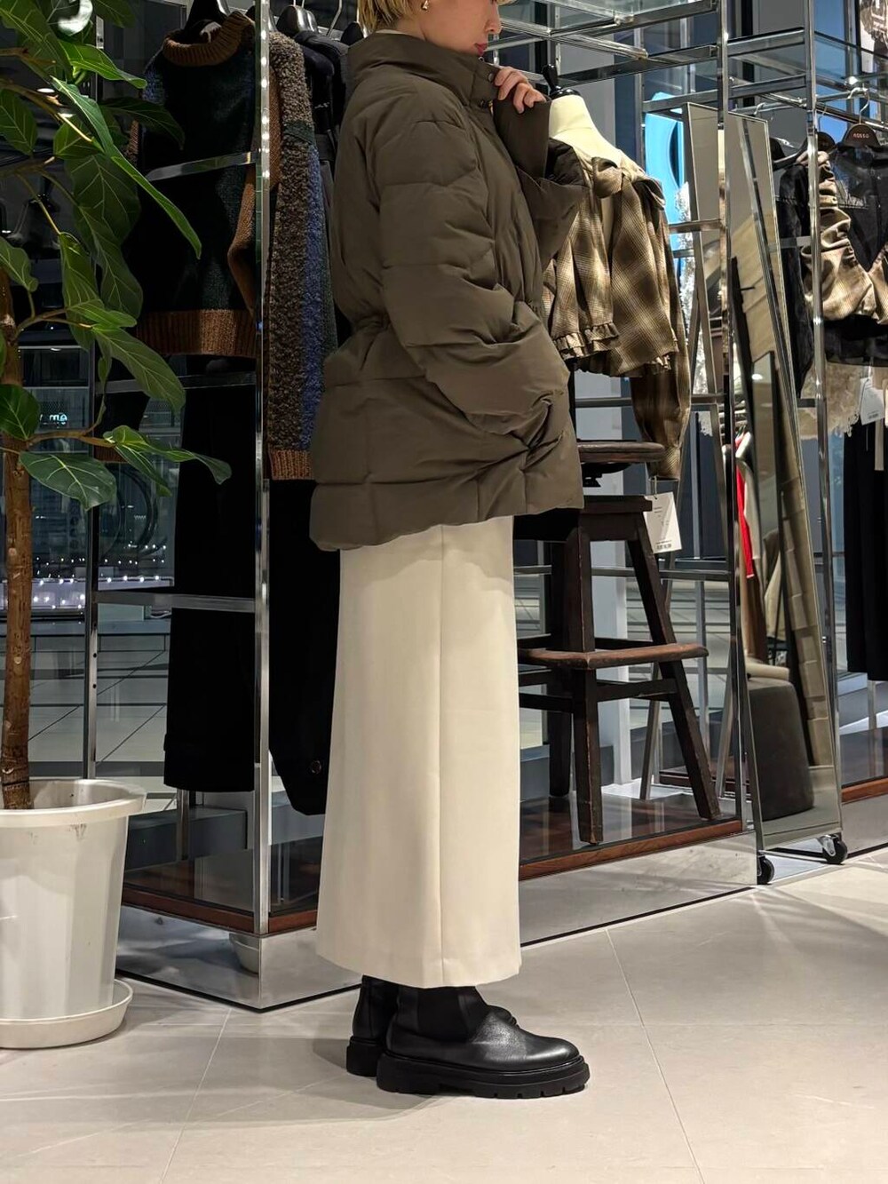 グリーン系のダウンジャケット/コート、ブラック系のニット/セーター、ベージュ系のスカートを着用したレディースの秋コーディネートの2枚目の写真