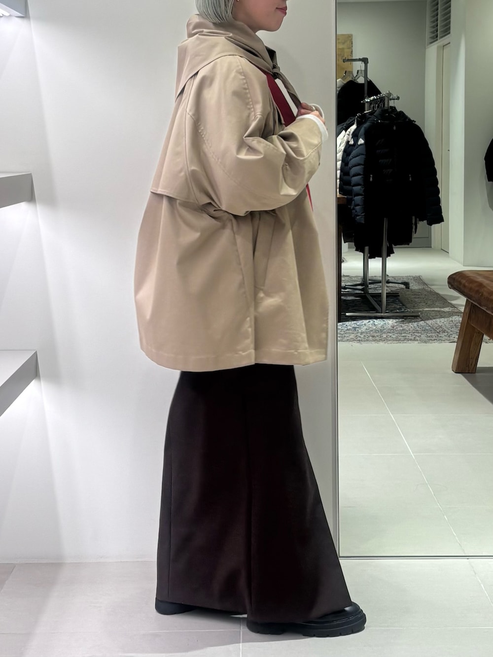 ブラウン系のスカート、レッド系のトートバッグ、ベージュ系のトレンチコートを着用したレディースの冬コーディネートの2枚目の写真