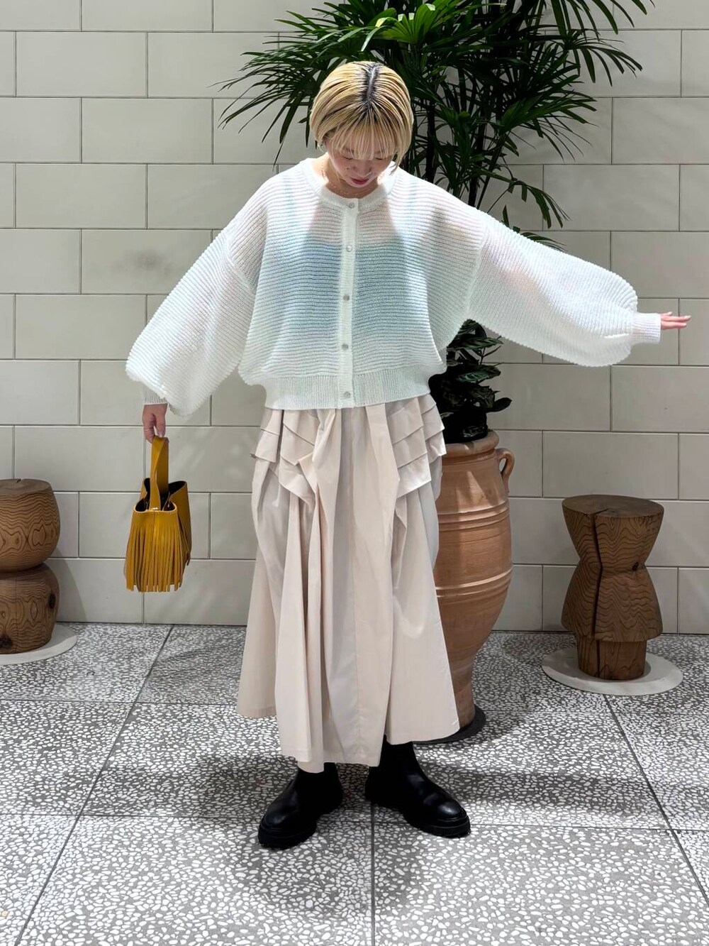 ホワイト系のスカート、ホワイト系のカーディガン/ボレロ、イエロー系のハンドバッグを着用したレディースの冬コーディネートの3枚目の写真