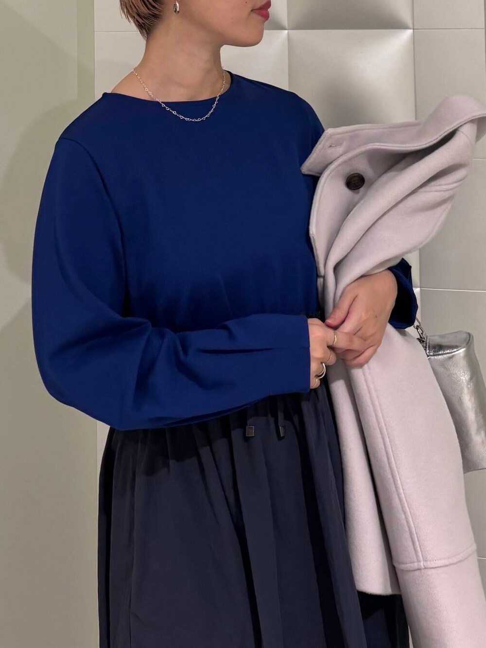 グレー系のピーコート、ブラック系のブーツ、シルバー系のショルダーバッグを着用したレディースの冬コーディネートの5枚目の写真