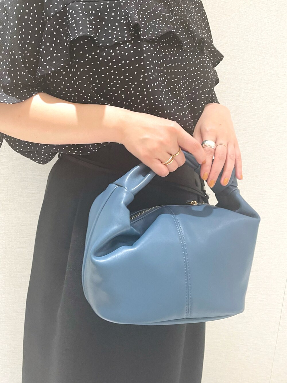 ブラック系のシャツ/ブラウス、ブラック系のスカート、ブルー系のハンドバッグを着用したレディースの春コーディネートの3枚目の写真