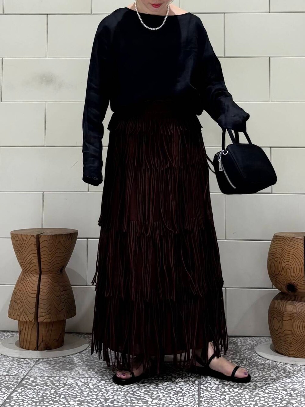 ブラック系のシャツ/ブラウス、ブラック系のボストンバッグ、ブラウン系のスカートを着用したレディースの春コーディネートの3枚目の写真