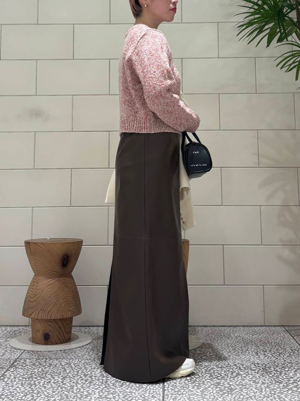 ホワイト系のスニーカー、ブラック系のボストンバッグ、ブラウン系のスカートを着用したレディースの冬コーディネートの5枚目の写真