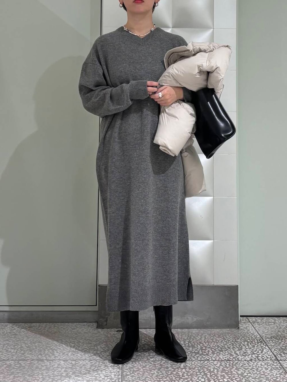 ブラック系のトートバッグ、ブラック系のブーツ、ホワイト系のダウンジャケット/コートを着用したレディースの冬コーディネートの5枚目の写真