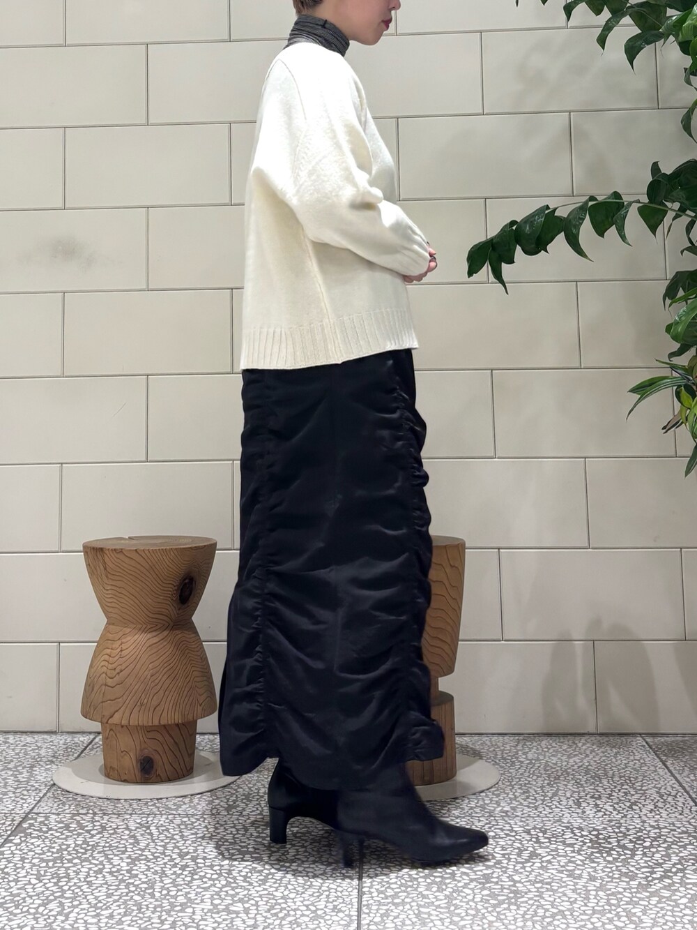 ブラック系のスカート、ホワイト系のニット/セーター、ブラック系のTシャツ/カットソーを着用したレディースの冬コーディネートの2枚目の写真