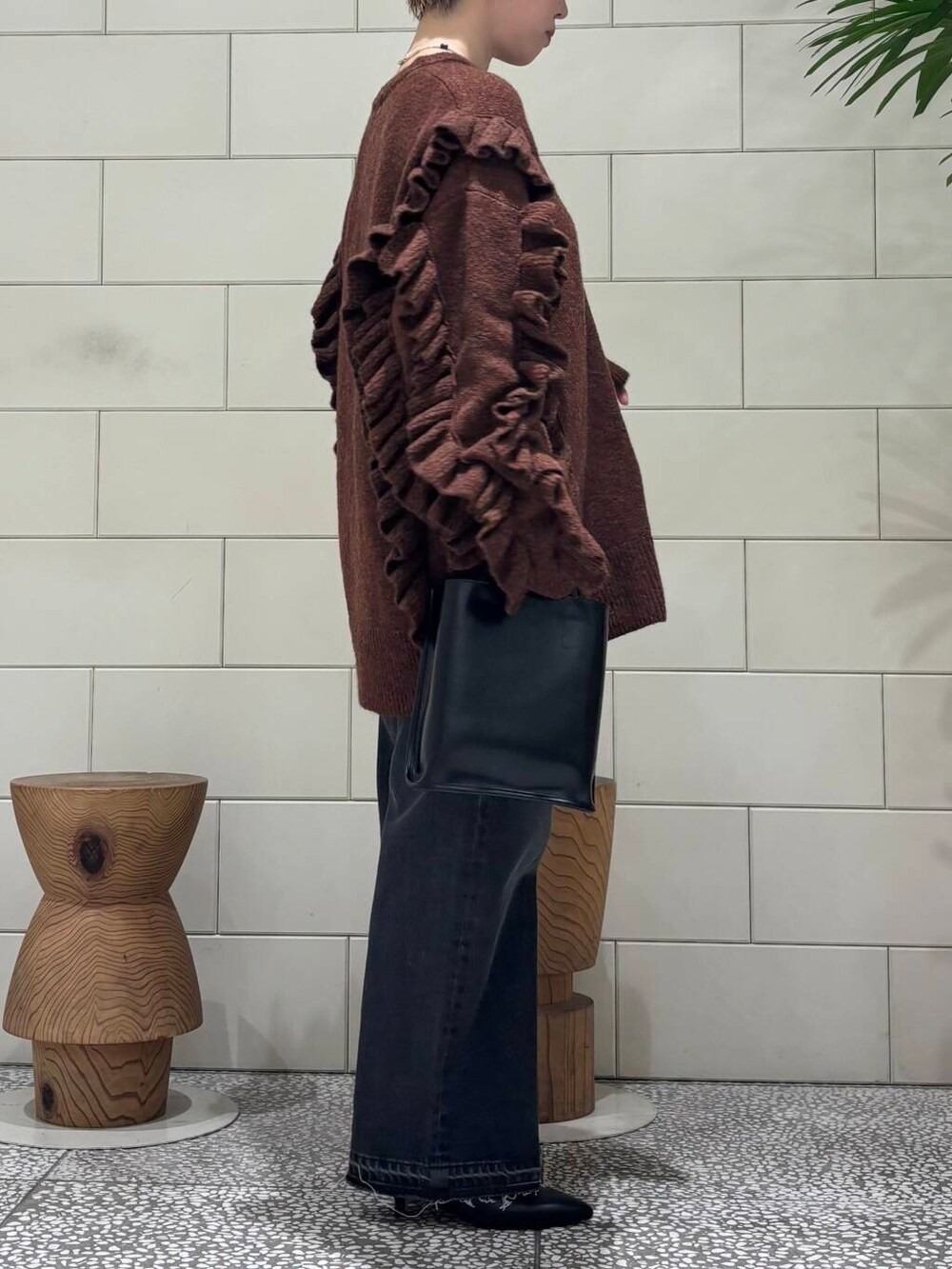 ブラック系のデニムパンツ、ブラック系のトートバッグ、ブラウン系のブーツを着用したレディースの冬コーディネートの2枚目の写真