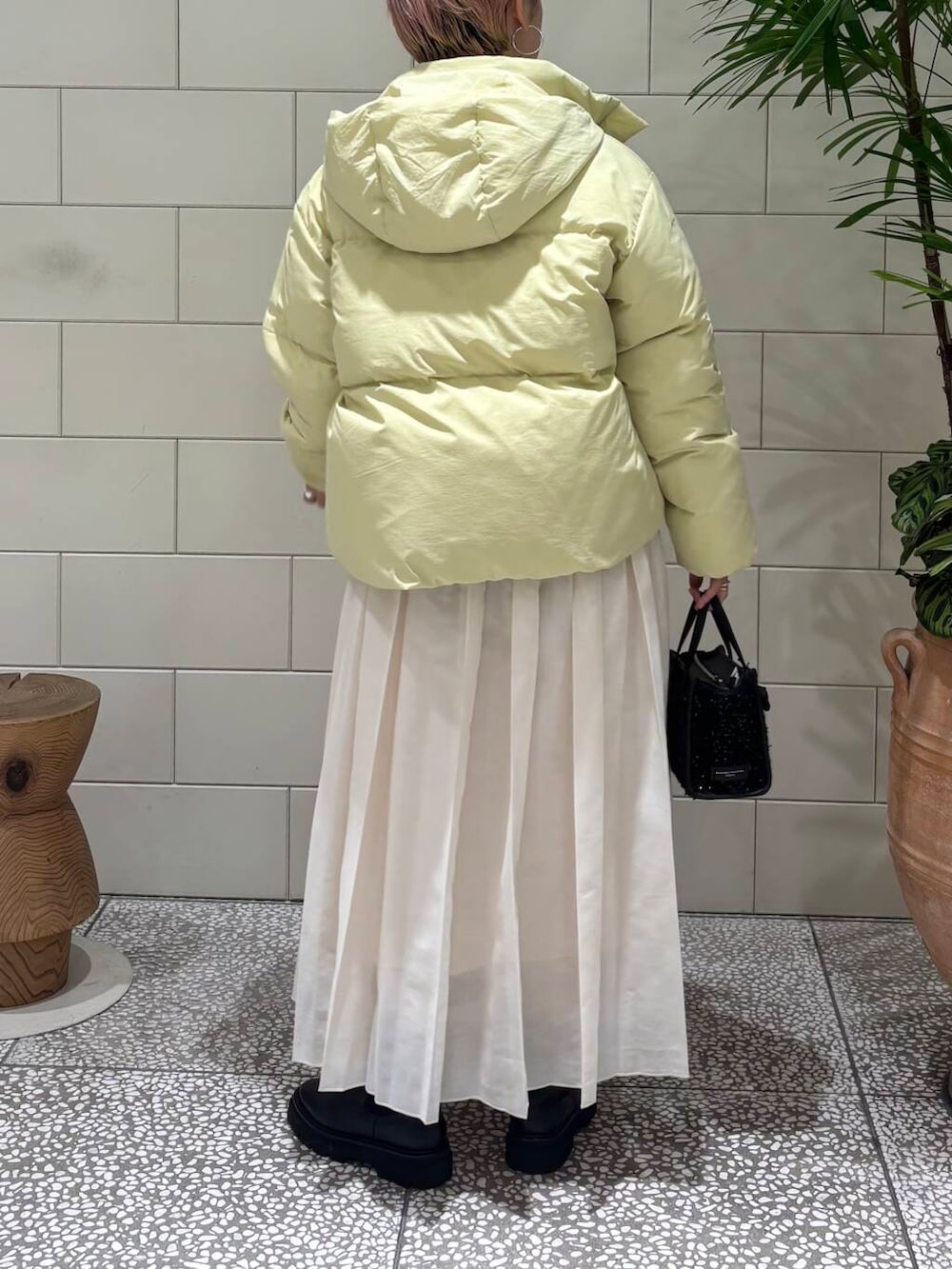 ホワイト系のニット/セーター、ホワイト系のスカート、イエロー系のダウンジャケット/コートを着用したレディースの冬コーディネートの4枚目の写真