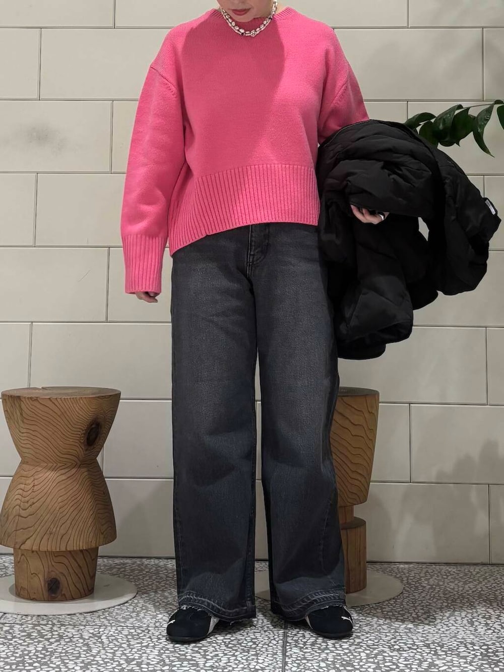ブラック系のデニムパンツ、ピンク系のニット/セーター、シルバー系のショルダーバッグを着用したレディースの冬コーディネートの5枚目の写真