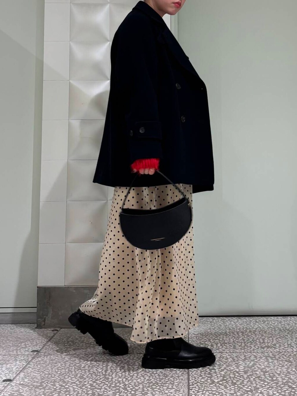 ブルー系のピーコート、レッド系のカーディガン/ボレロ、ベージュ系のスカートを着用したレディースの冬コーディネートの2枚目の写真