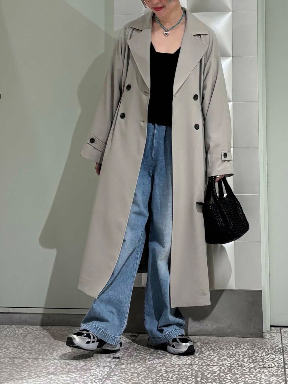 ブルー系のデニムパンツ、グリーン系のトレンチコート、ブラック系のスニーカーを着用したレディースの春コーディネートの2枚目の写真