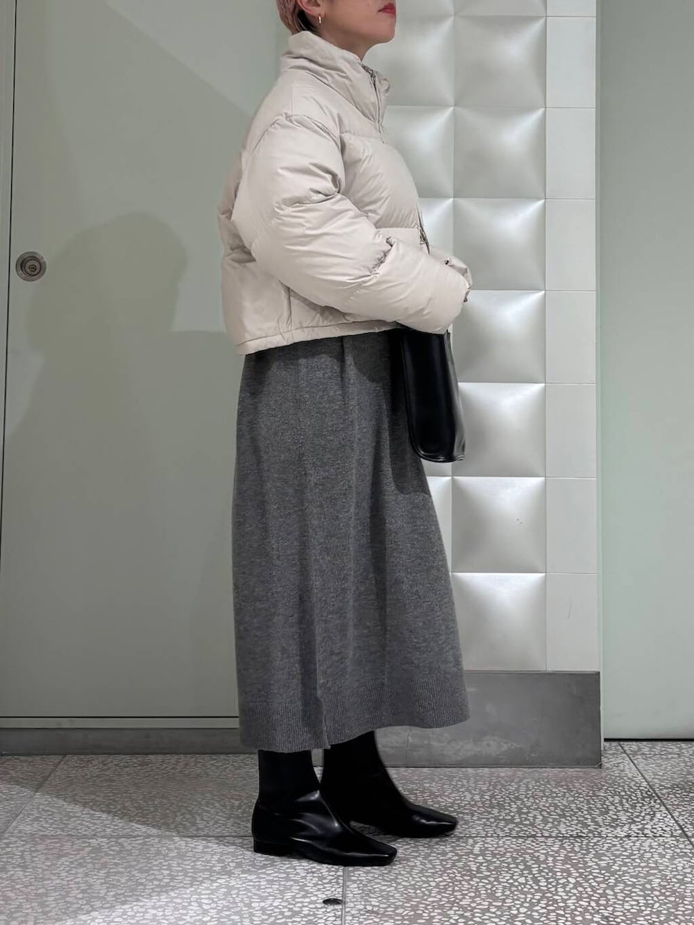 ブラック系のトートバッグ、ブラック系のブーツ、ホワイト系のダウンジャケット/コートを着用したレディースの冬コーディネートの3枚目の写真