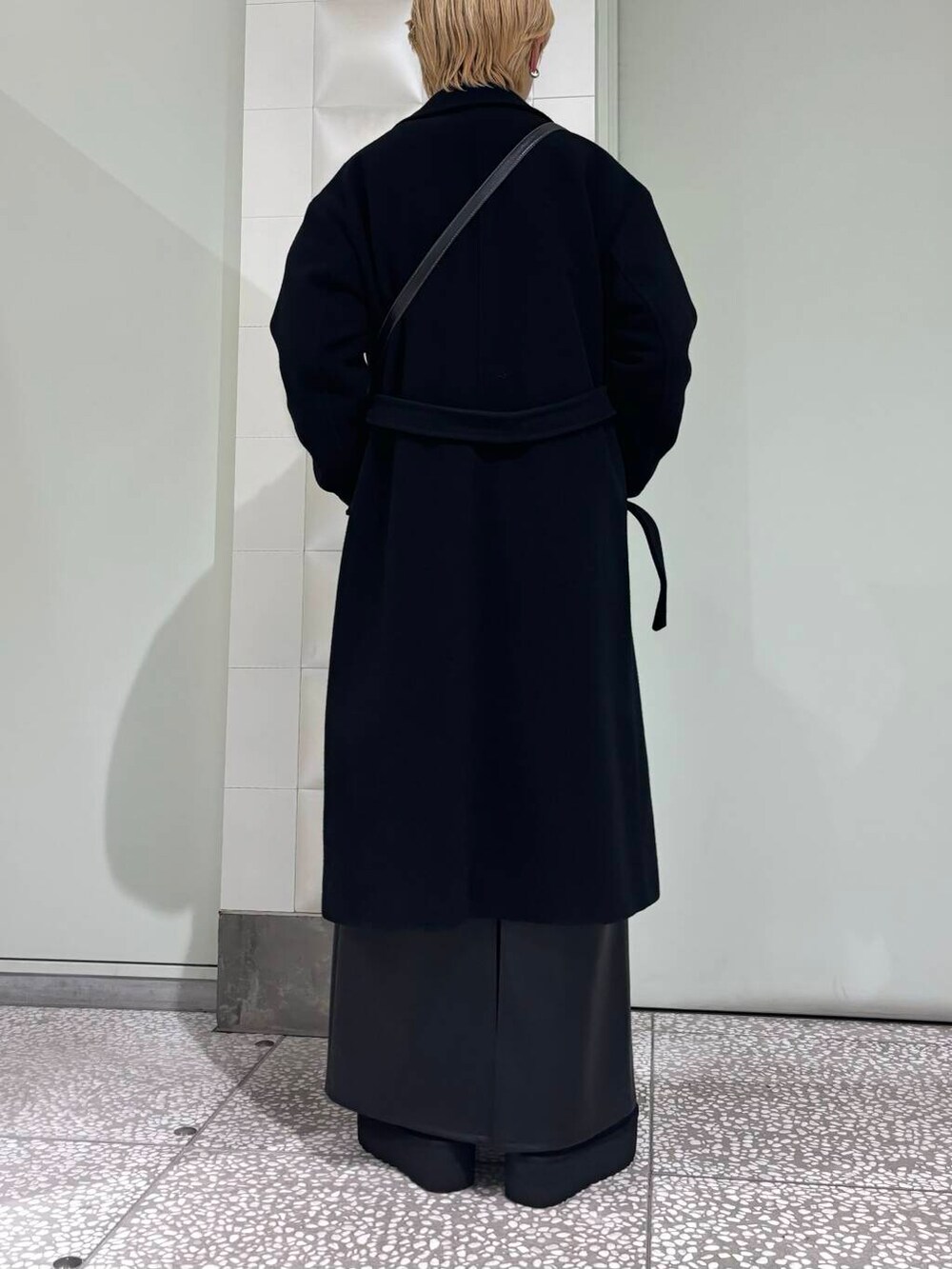 ブラック系のチェスターコート、ブラック系のスカート、ブラック系のブーツを着用したレディースの秋コーディネートの3枚目の写真