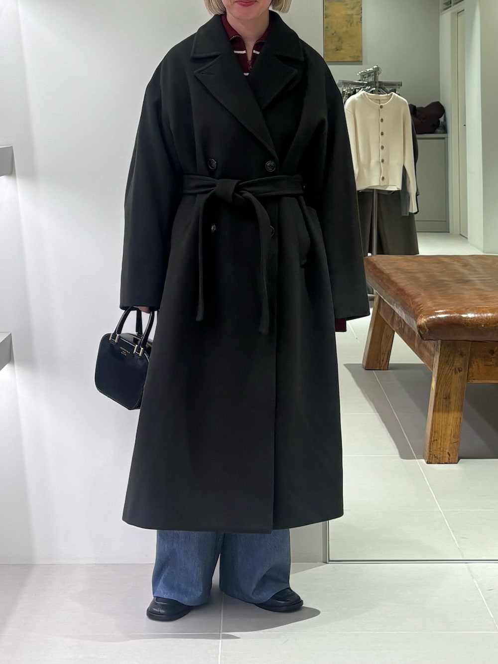 グリーン系のチェスターコート、ブルー系のその他パンツ、ブラック系のショルダーバッグを着用したレディースの秋コーディネートの3枚目の写真