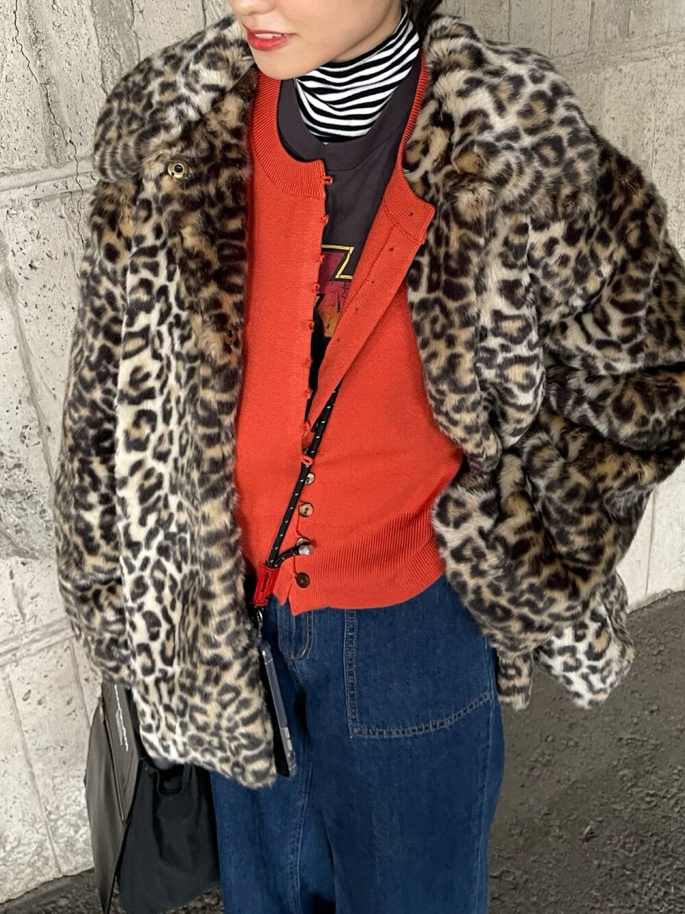 ブラック系のバッグ、ブラック系のパンプス、オレンジ系のカーディガン/ボレロを着用したレディースの冬コーディネートの2枚目の写真