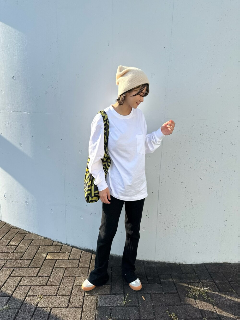 ホワイト系のスニーカー、イエロー系のバッグ、ブラック系のパンツを着用したレディースの秋コーディネートの2枚目の写真