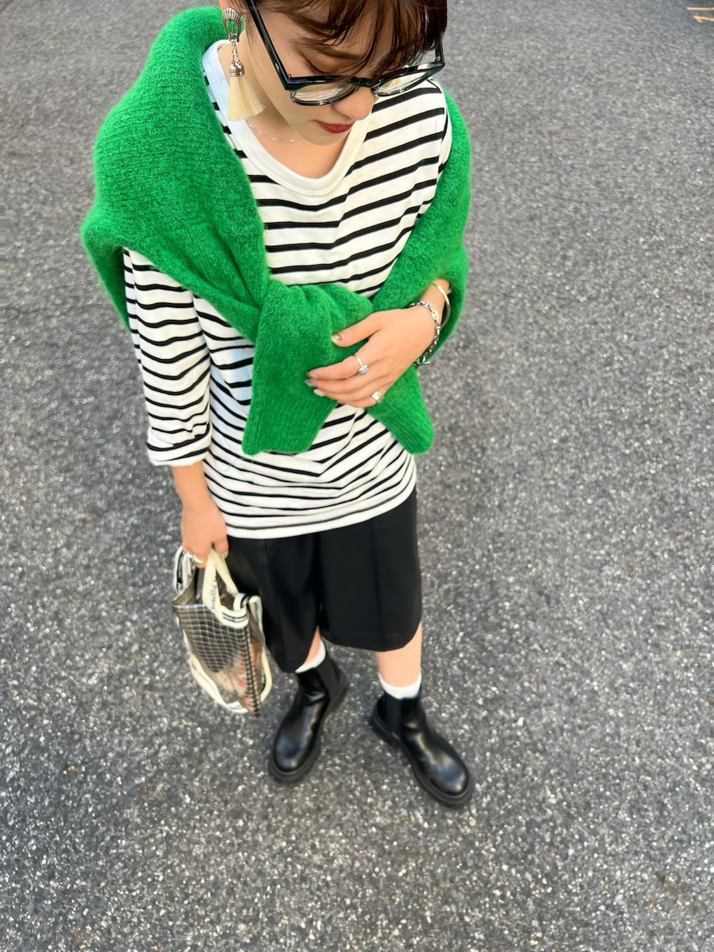 ブラック系のブーツ、グリーン系のニット/セーター、ブラック系のショルダーバッグを着用したレディースの秋コーディネートの2枚目の写真