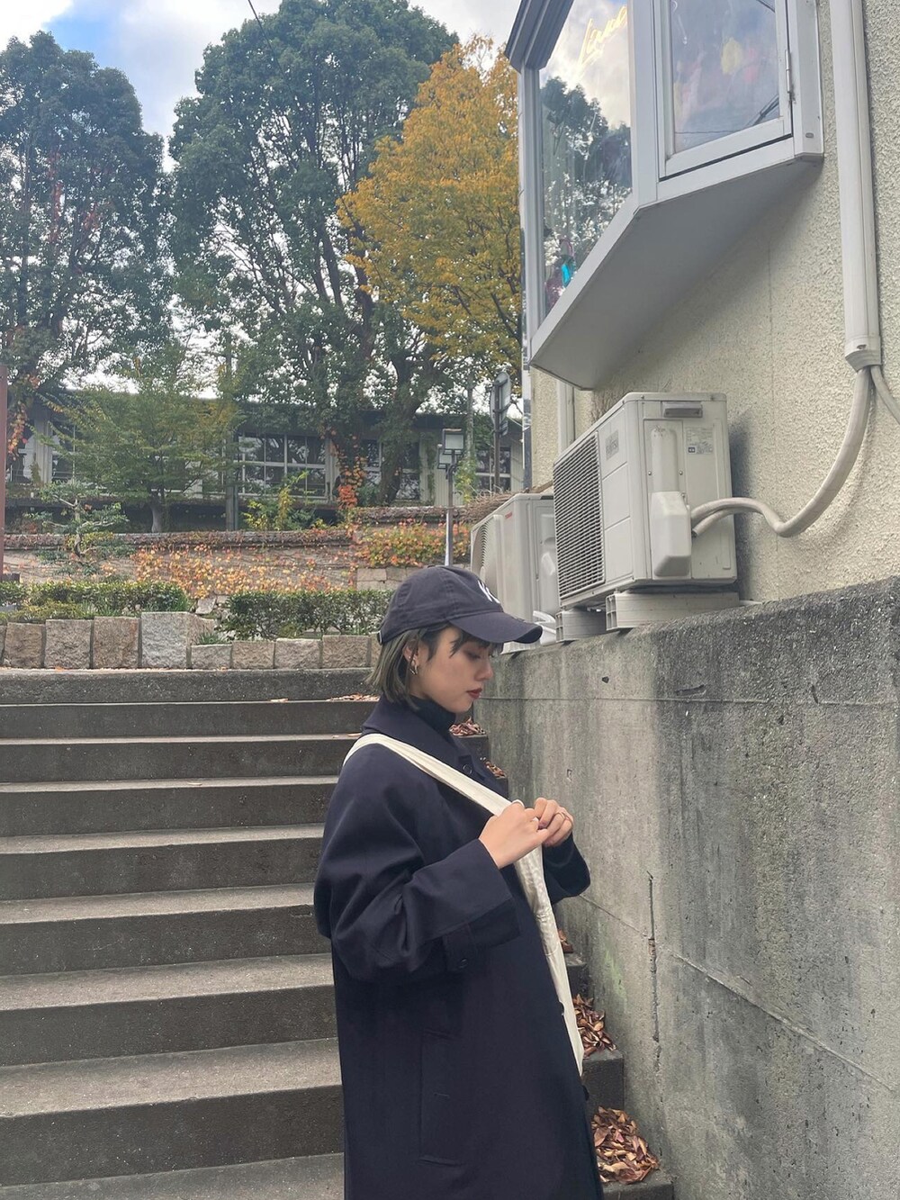 ブラック系のデニムスカート、ホワイト系のショルダーバッグ、ブラック系のブーツを着用したレディースの秋コーディネートの3枚目の写真