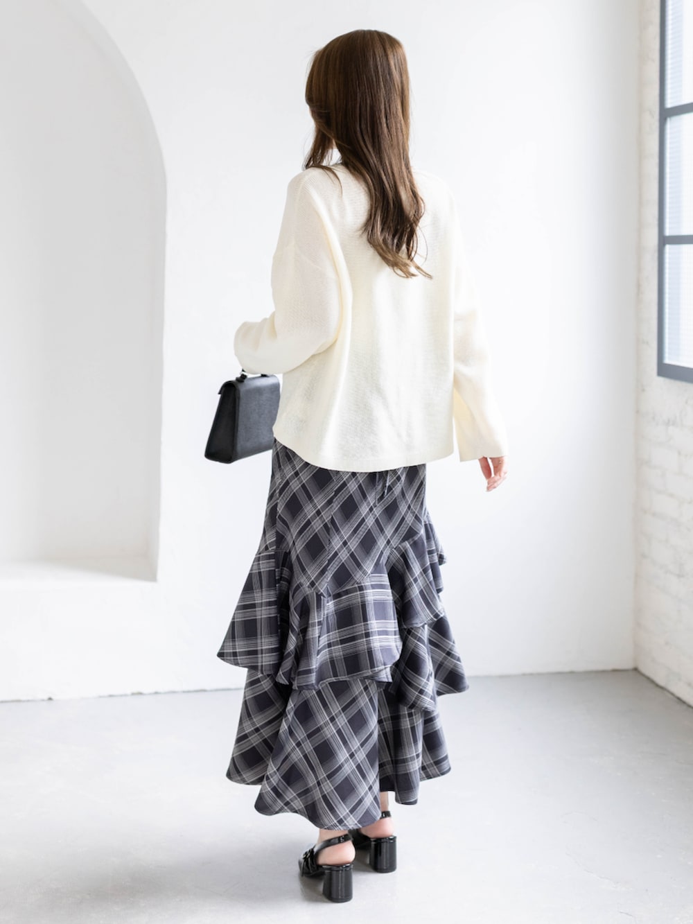 ブラック系のパンプス、ホワイト系のニット/セーター、ブラック系のスカートを着用したレディースの春コーディネートの3枚目の写真