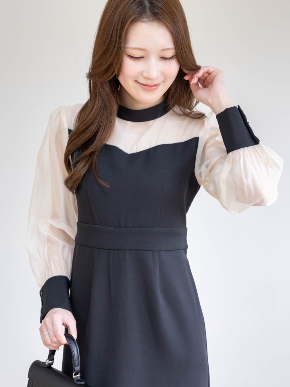 ブラック系のハンドバッグ、ブラック系のパンプス、ブラック系のワンピースを着用したレディースの春コーディネートの8枚目の写真