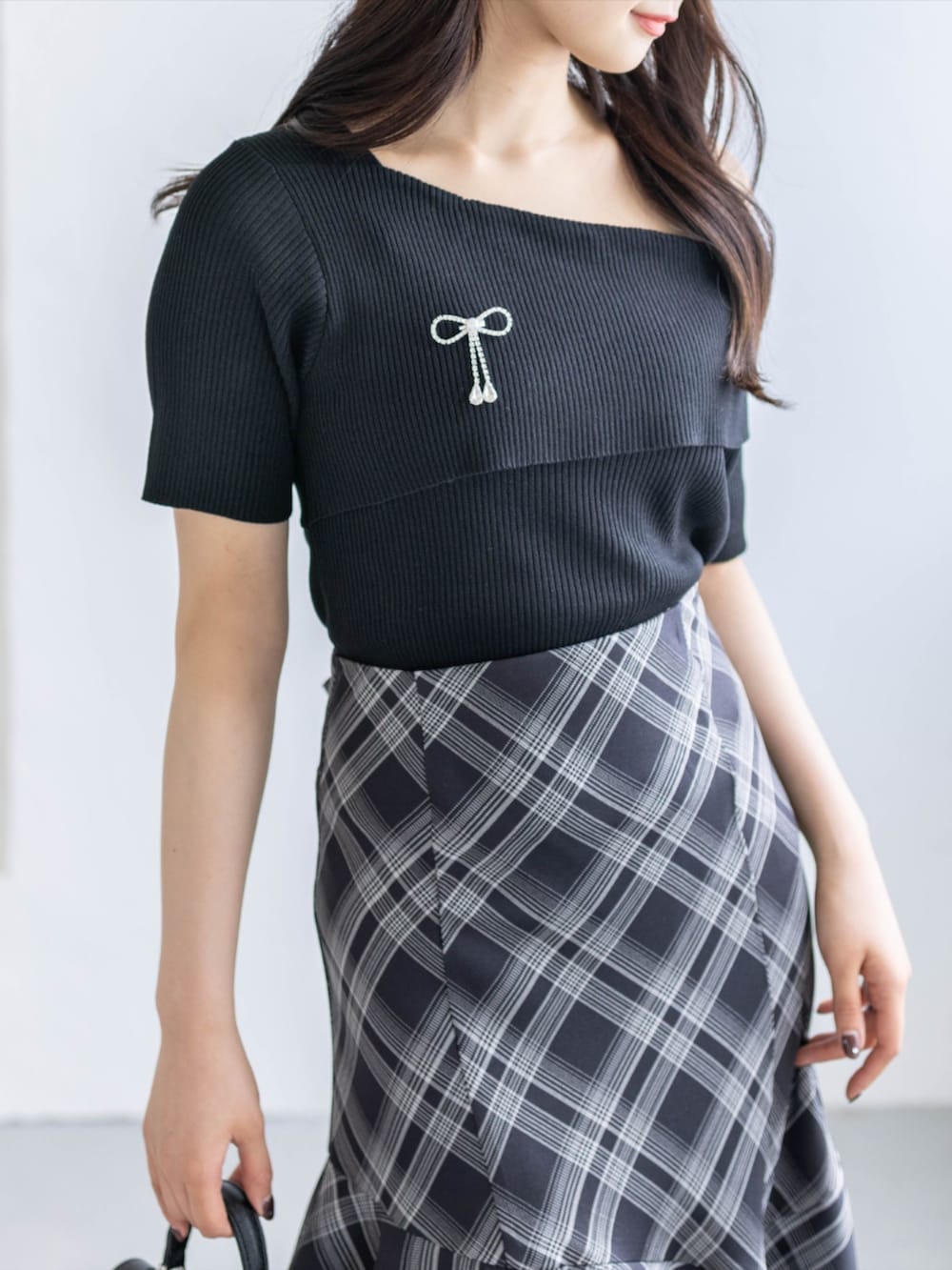 ブラック系のスカート、ブラック系のハンドバッグ、ブラック系のパンプスを着用したレディースの春コーディネートの4枚目の写真