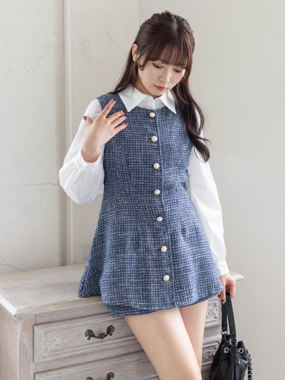 ブルー系のチュニック、ブラック系のハンドバッグ、ホワイト系のシャツ/ブラウスを着用したレディースの春コーディネートの3枚目の写真