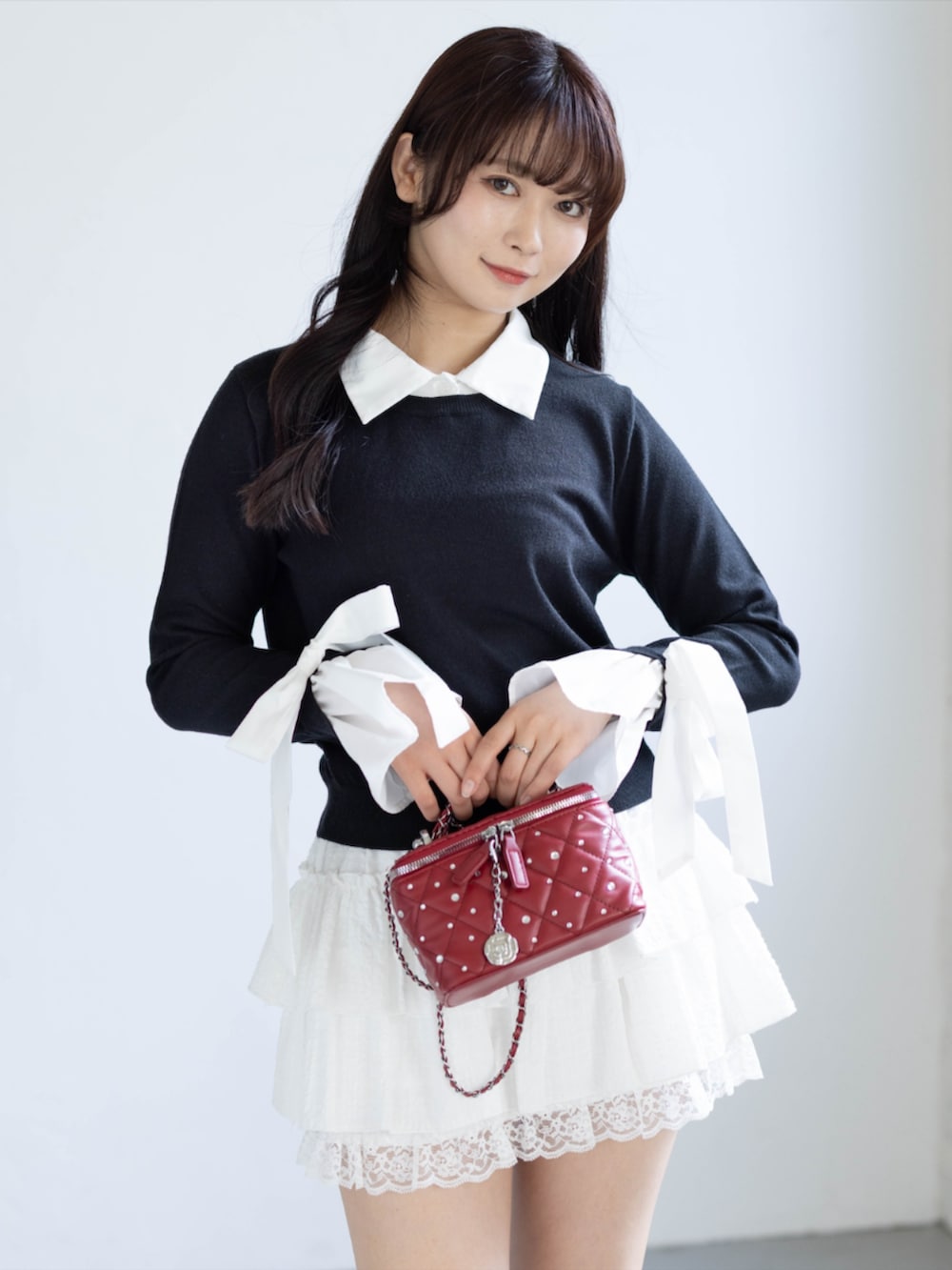レッド系のパンプス、ホワイト系のスカート、ブラック系のニット/セーターを着用したレディースの夏コーディネートの3枚目の写真