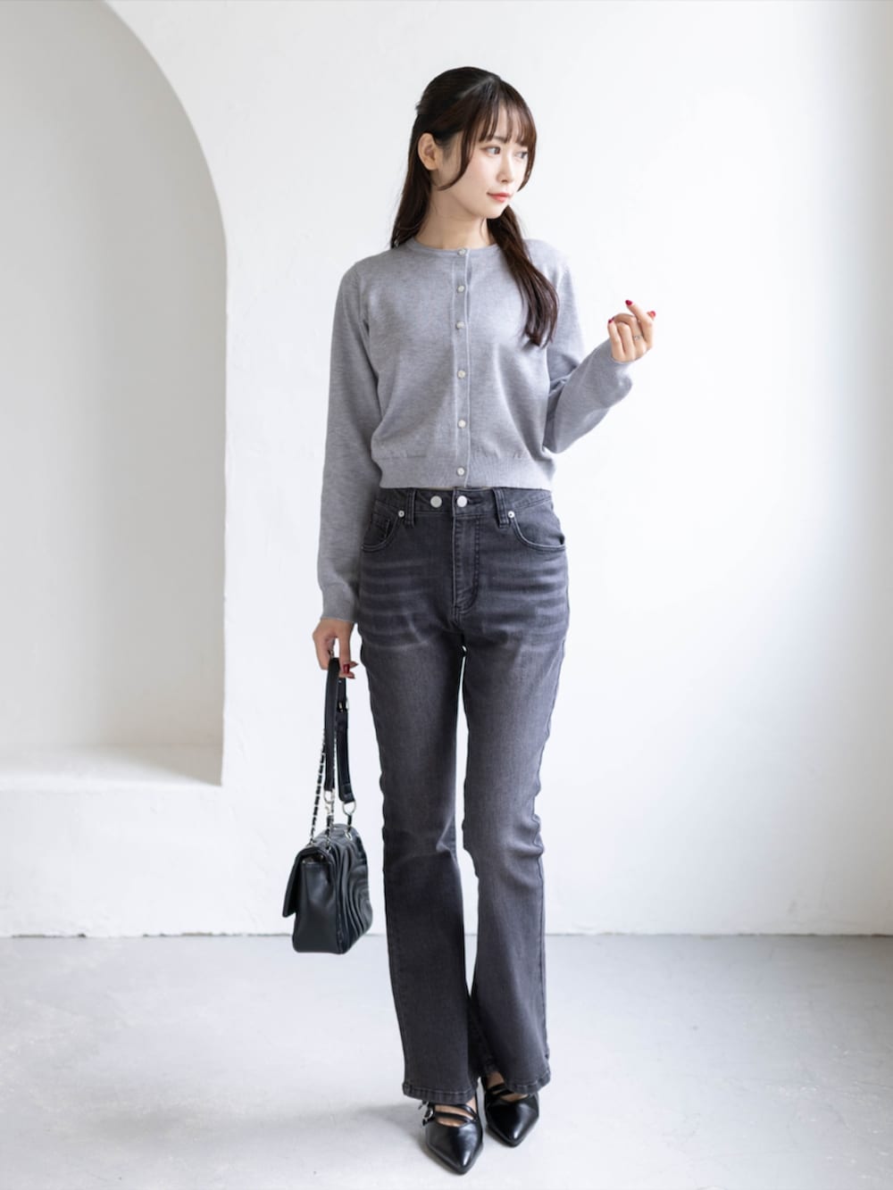 ブラック系のデニムパンツ、ブラック系のパンプス、グレー系のニット/セーターを着用したレディースの秋コーディネートの2枚目の写真