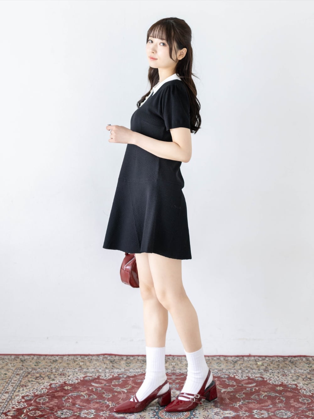 レッド系のパンプス、ブラック系のワンピースを着用したレディースの夏コーディネートの3枚目の写真