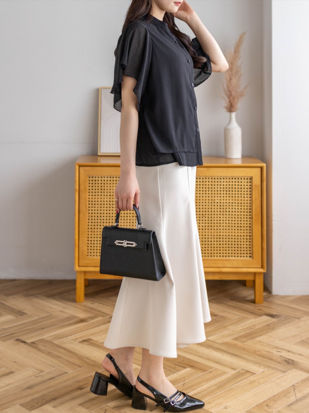 ブラック系のパンプス、ホワイト系のスカート、ブラック系のハンドバッグを着用したレディースの夏コーディネートの5枚目の写真