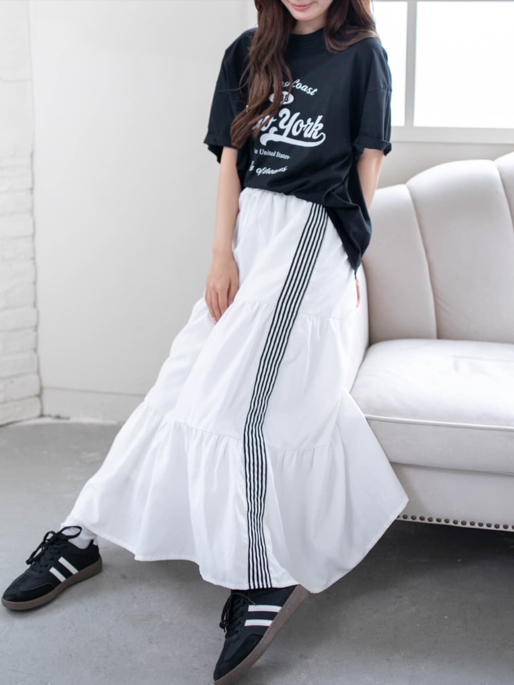 ブラック系のスニーカー、ホワイト系のスカート、ブラック系のTシャツ/カットソーを着用したレディースの夏コーディネートの6枚目の写真