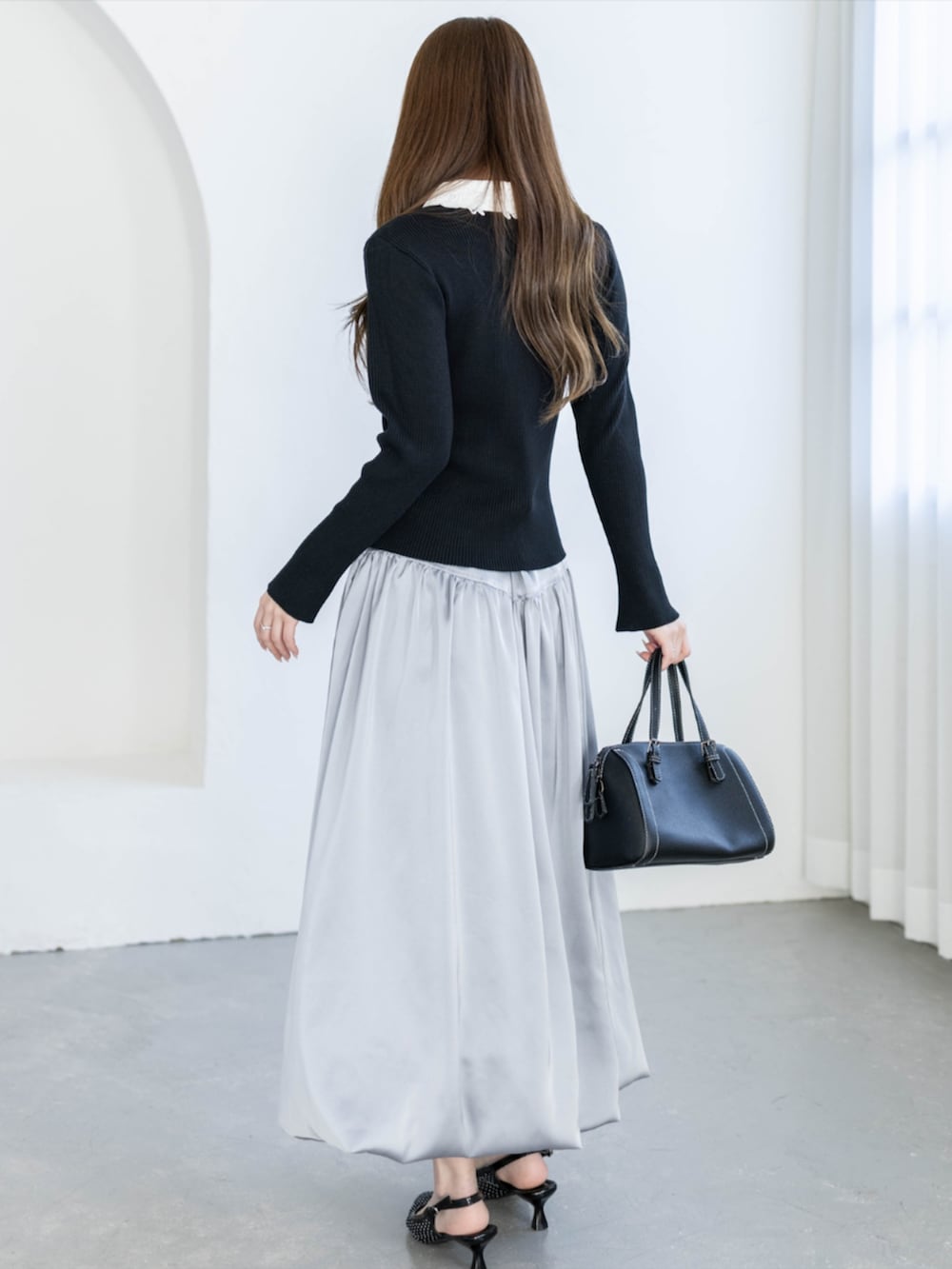 ブラック系のパンプス、グレー系のスカート、ブラック系のニット/セーターを着用したレディースの夏コーディネートの2枚目の写真