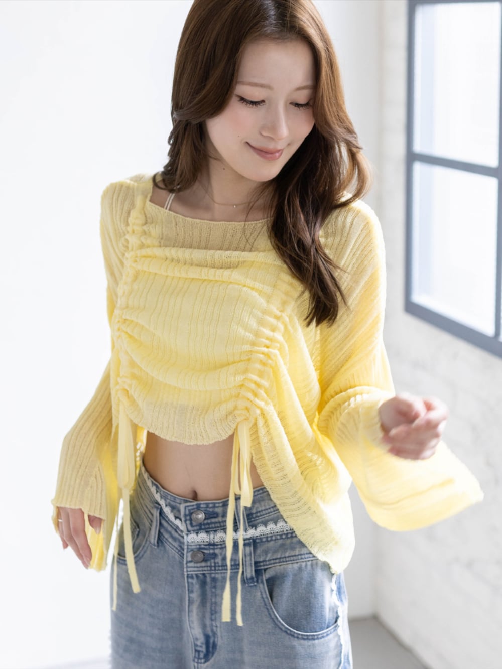 ブルー系のデニムパンツ、ホワイト系のパンプス、イエロー系のニット/セーターを着用したレディースの春コーディネートの3枚目の写真