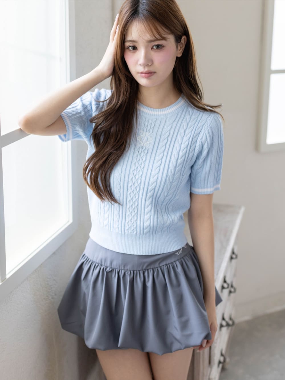 シルバー系のパンプス、グレー系のスカート、ブルー系のニット/セーターを着用したレディースの夏コーディネートの4枚目の写真