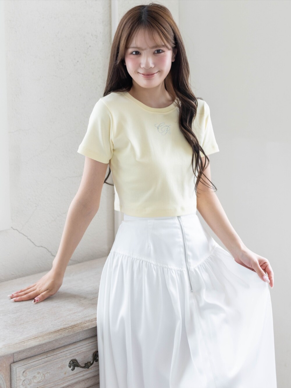 ホワイト系のスカート、ホワイト系のパンプス、イエロー系のTシャツ/カットソーを着用したレディースの夏コーディネートの3枚目の写真