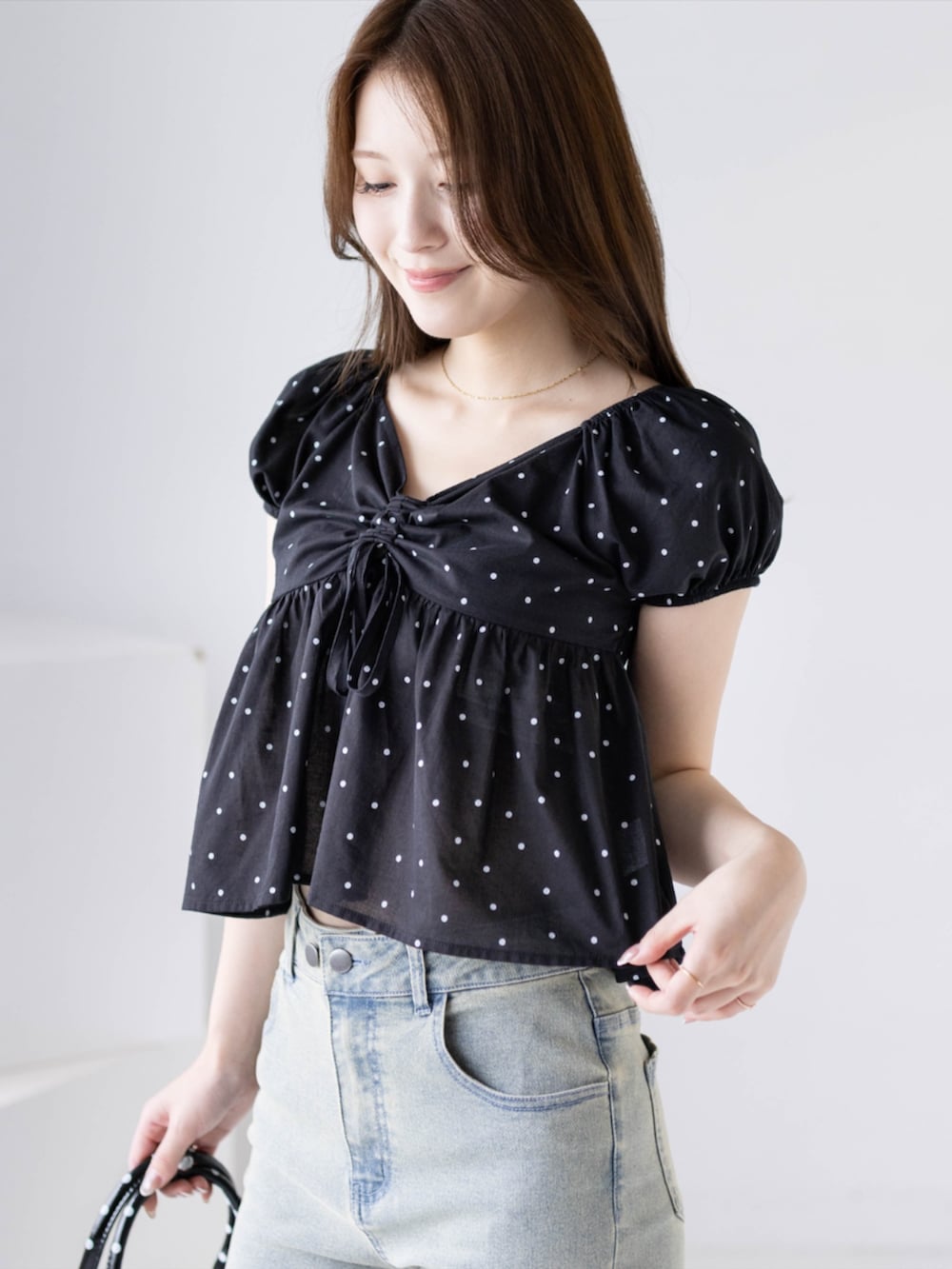 ブラック系のパンプス、ブルー系のデニムパンツ、ブラック系のボストンバッグを着用したレディースの夏コーディネートの6枚目の写真