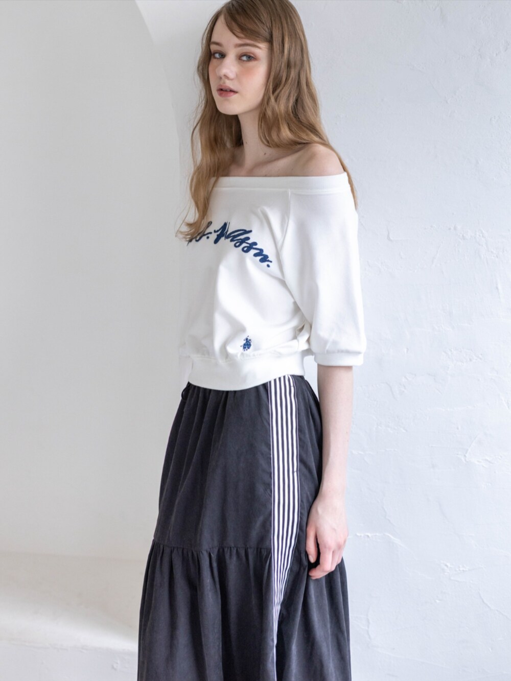 ブラック系のスニーカー、ブラック系のスカート、ホワイト系のTシャツ/カットソーを着用したレディースの夏コーディネートの3枚目の写真