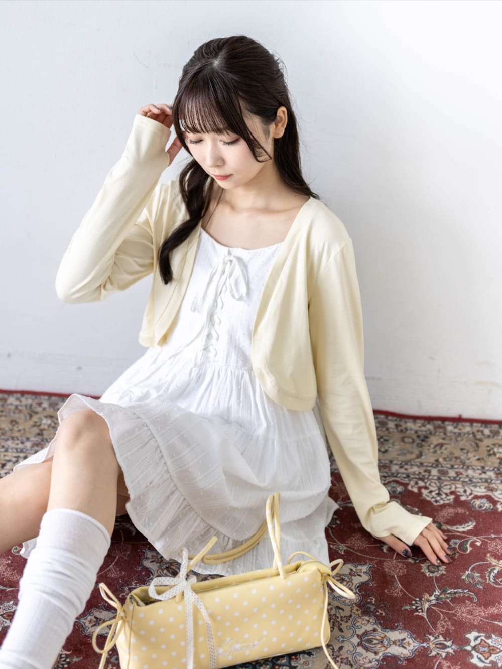 ホワイト系のワンピース、ホワイト系のパンプス、イエロー系のカーディガン/ボレロを着用したレディースの夏コーディネートの6枚目の写真