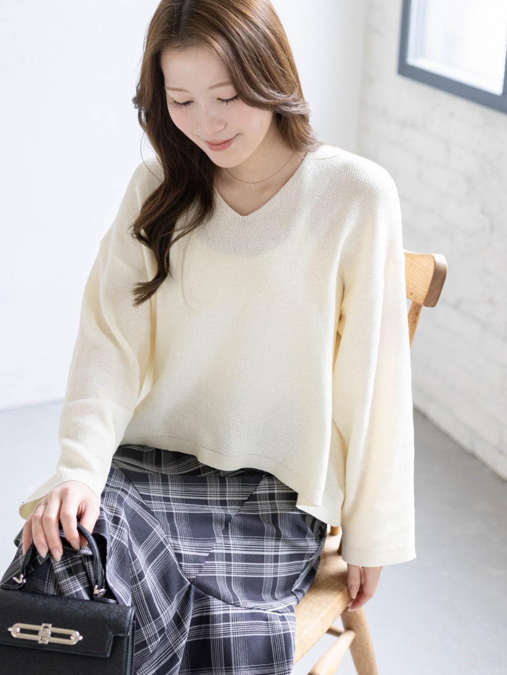 ブラック系のパンプス、ホワイト系のニット/セーター、ブラック系のスカートを着用したレディースの春コーディネートの6枚目の写真