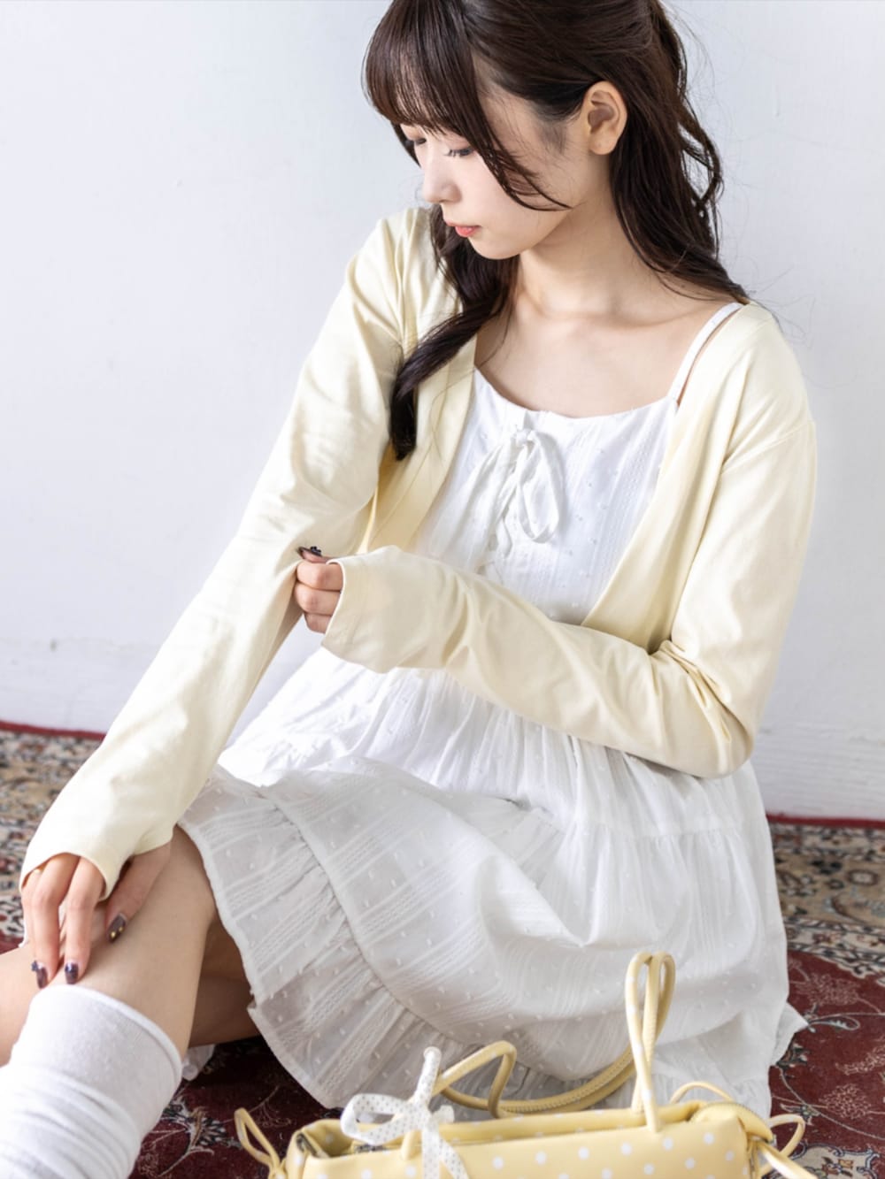 ホワイト系のワンピース、ホワイト系のパンプス、イエロー系のカーディガン/ボレロを着用したレディースの夏コーディネートの9枚目の写真