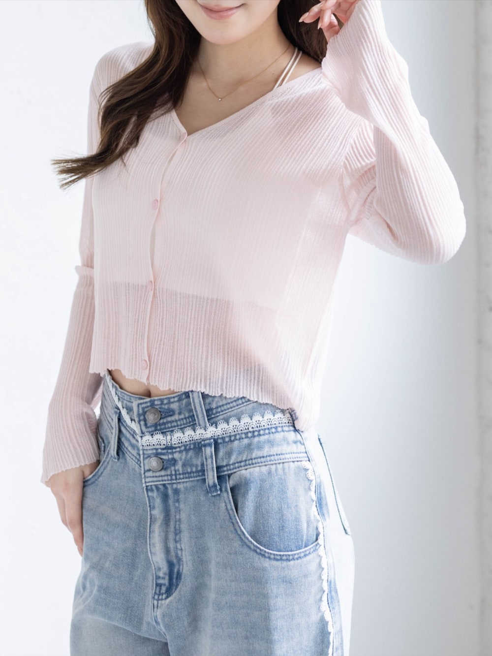 ブルー系のデニムパンツ、ホワイト系のパンプス、ピンク系のカーディガン/ボレロを着用したレディースの春コーディネートの5枚目の写真