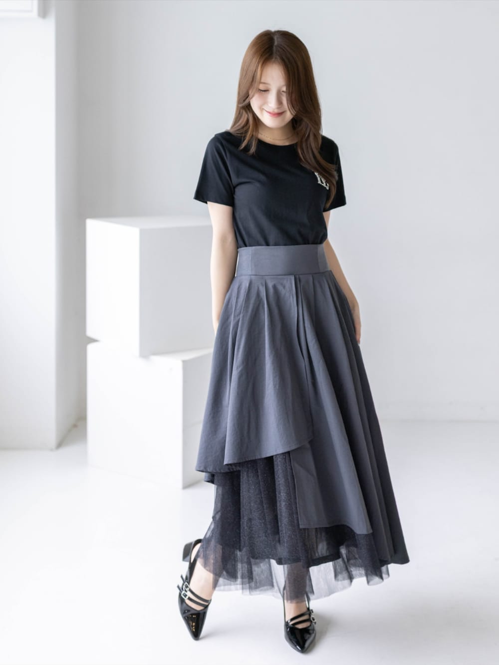 ブラック系のパンプス、グレー系のスカート、ブラック系のTシャツ/カットソーを着用したレディースの夏コーディネートの2枚目の写真