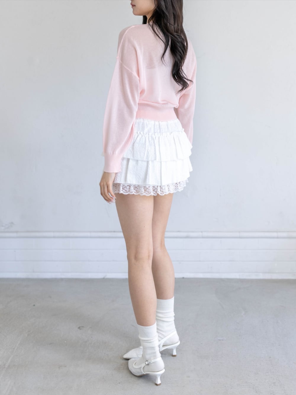 ホワイト系のスカート、ホワイト系のパンプス、ピンク系のカーディガン/ボレロを着用したレディースの春コーディネートの2枚目の写真