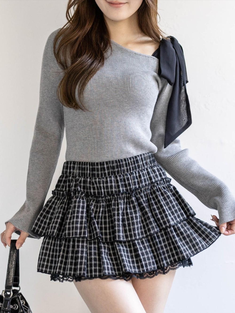 ブラック系のブーツ、ブラック系のスカート、ブラック系のハンドバッグを着用したレディースの冬コーディネートの6枚目の写真