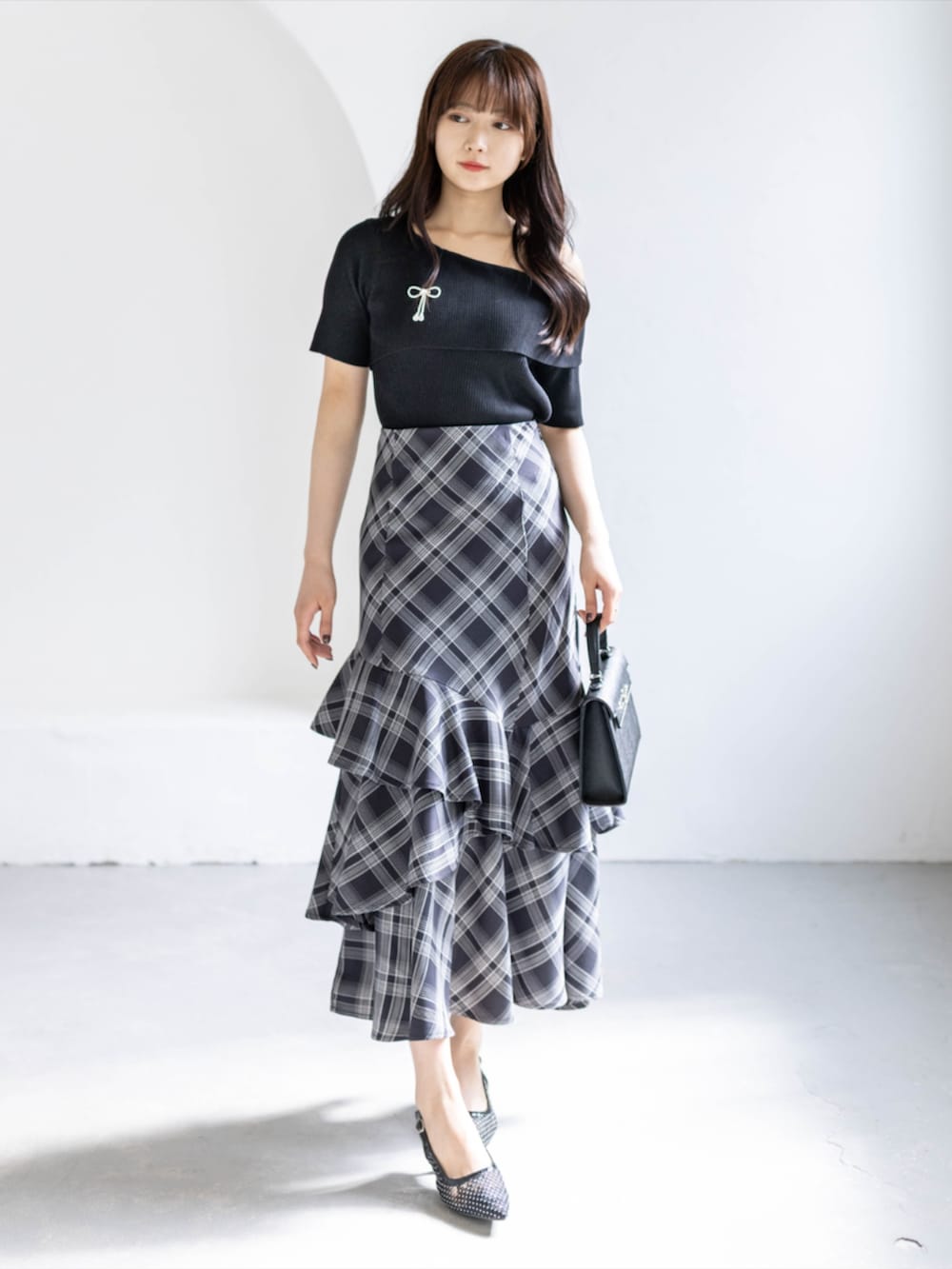 ブラック系のスカート、ブラック系のハンドバッグ、ブラック系のパンプスを着用したレディースの春コーディネートの2枚目の写真