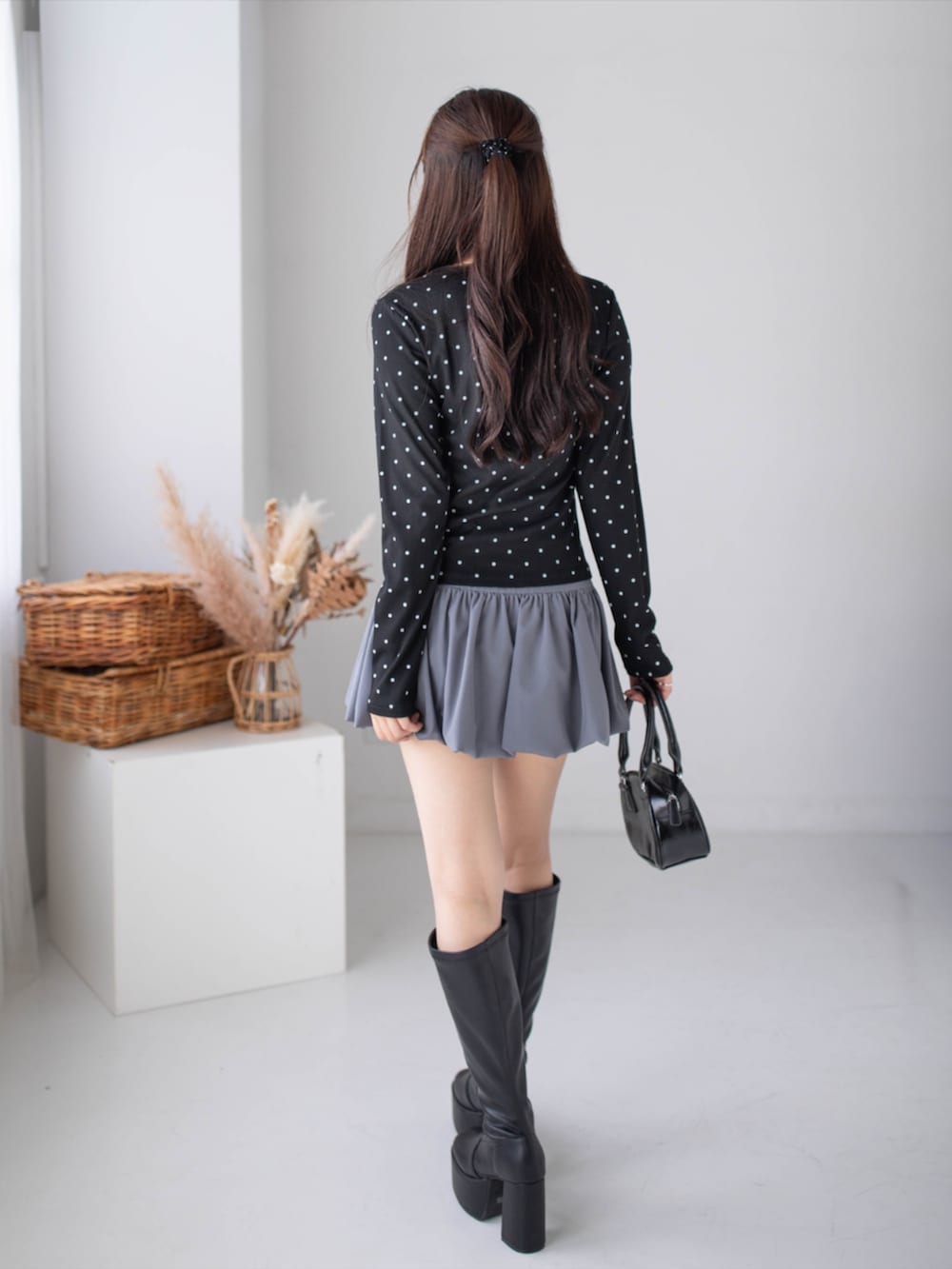グレー系のスカート、ブラック系のブーツ、ブラック系のTシャツ/カットソーを着用したレディースの秋コーディネートの2枚目の写真