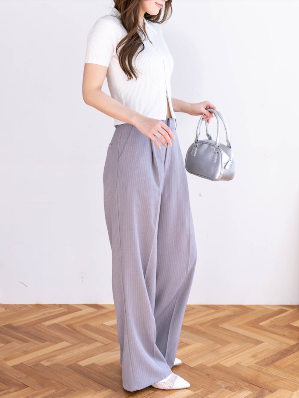 グレー系のスラックス、ホワイト系のパンプス、ホワイト系のニット/セーターを着用したレディースの春コーディネートの3枚目の写真