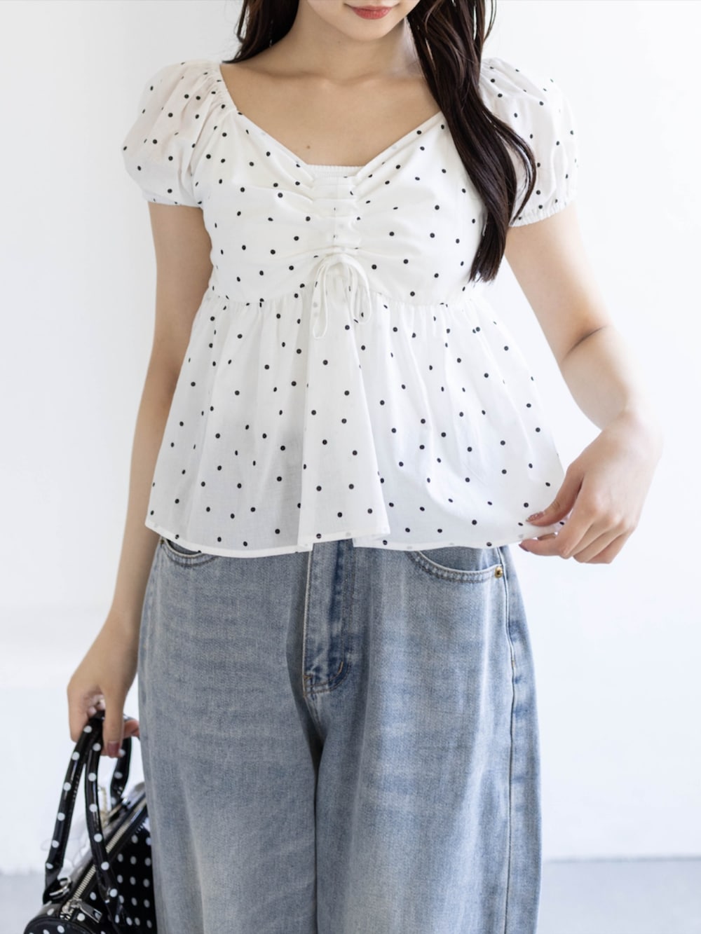 ブラック系のパンプス、ブルー系のデニムパンツ、ブラック系のボストンバッグを着用したレディースの夏コーディネートの5枚目の写真
