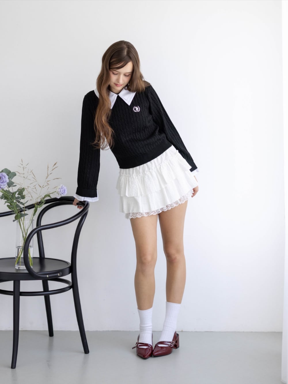 レッド系のパンプス、ホワイト系のスカート、ブラック系のニット/セーターを着用したレディースの秋コーディネートの2枚目の写真